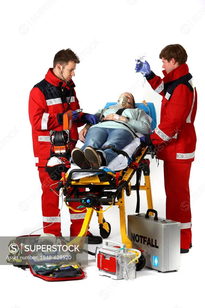 Paramedics with emergency equipment, first aid kit with bandages, medication, a defibrillator, ECG, breathing apparatus, recuscitating a patient and g...