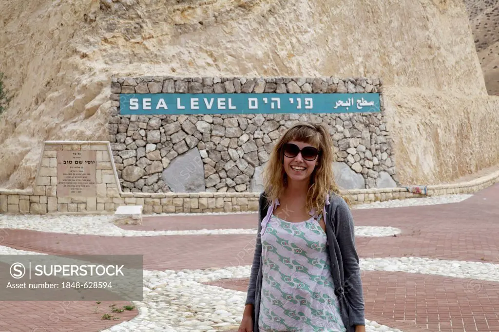 Woman in front of the sea-level indicator, on the road from Jerusalem to the Dead Sea, West Bank, Israel, Middle East