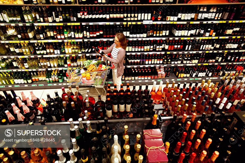 Woman shopping in the beverage section, sparkling wine, champagne, shelves, self-service, Germany, Europe