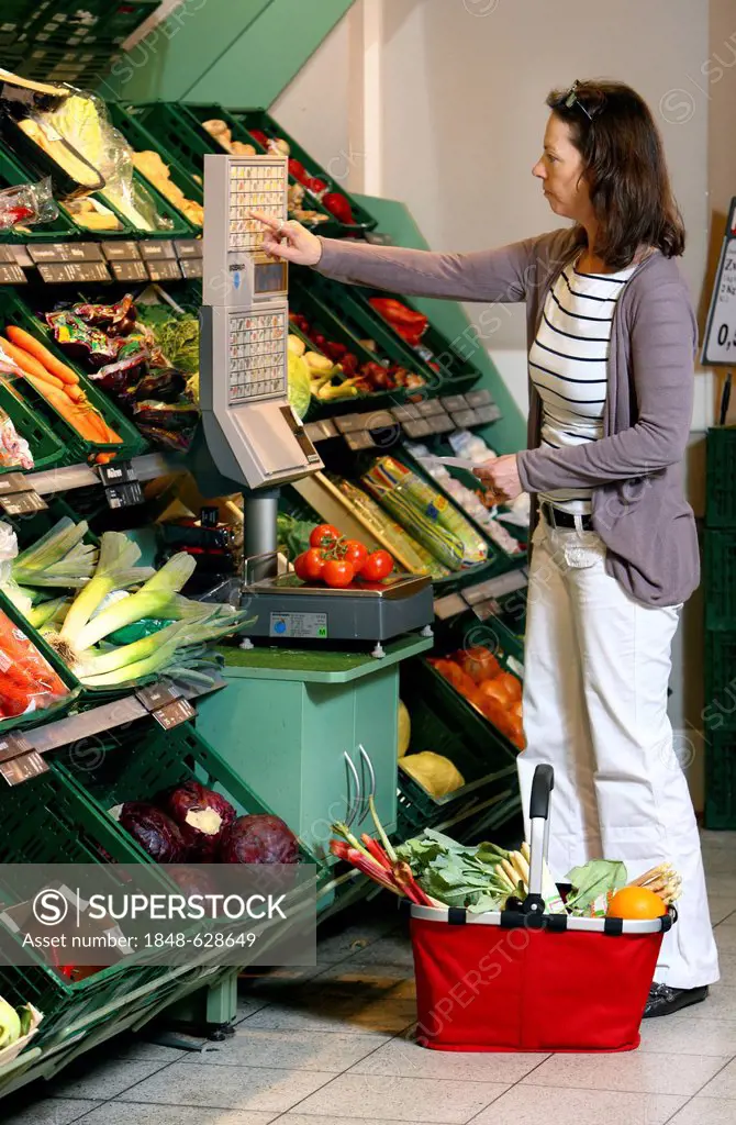 Woman weighing vegetables in the fruit and vegetable section of a self-service grocery department, supermarket, Germany, Europe