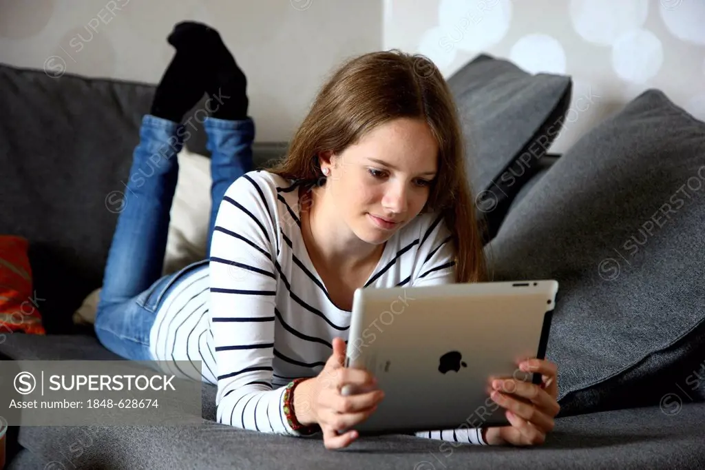 Girl playing at home with an iPad, tablet computer, wireless internet access