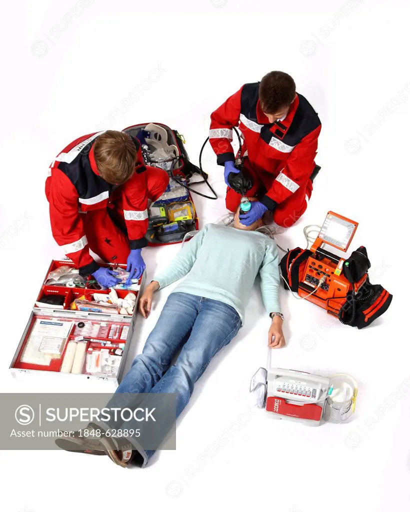 Paramedics with emergency equipment, a first aid kit with bandages, medication, a defibrillator, ECG, breathing apparatus, recuscitating a patient, pr...