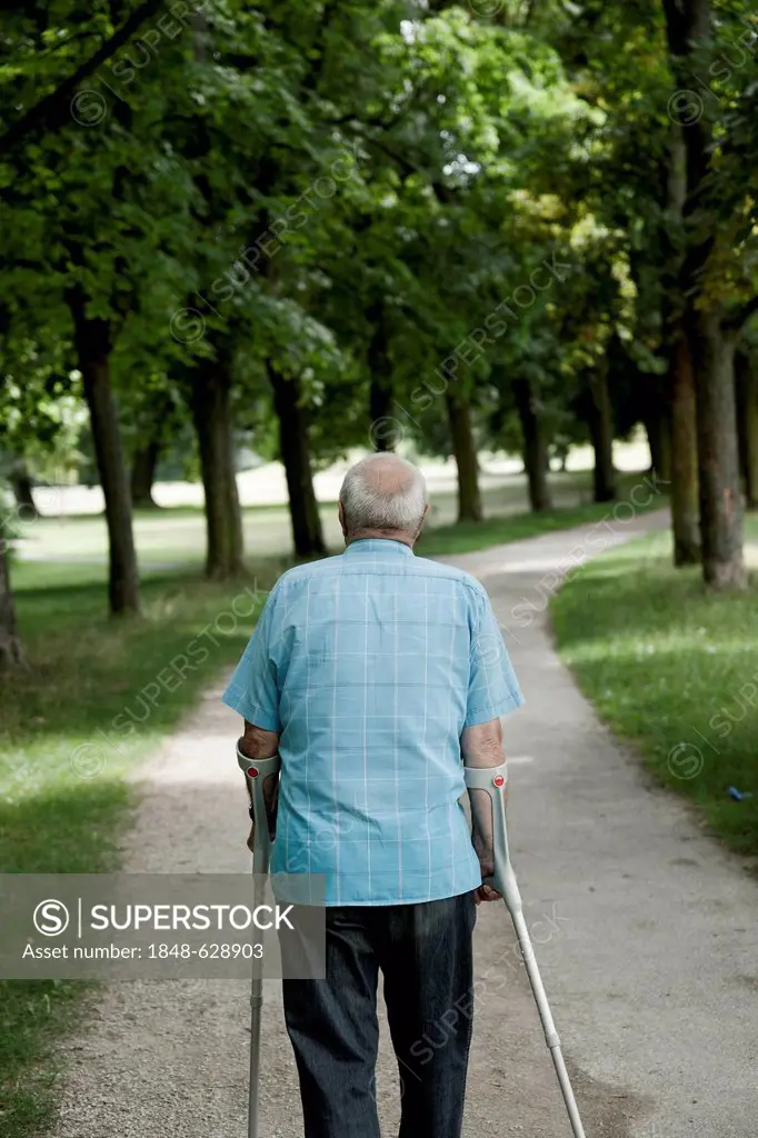 Elderly man with crutches, walk in the park