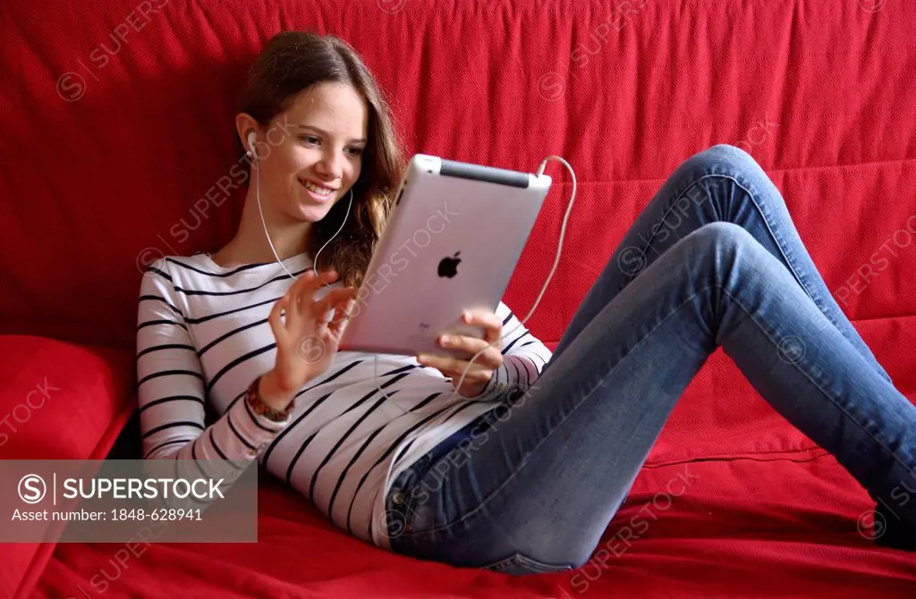 Girl listening to music at home with an iPad, tablet computer, wireless internet access