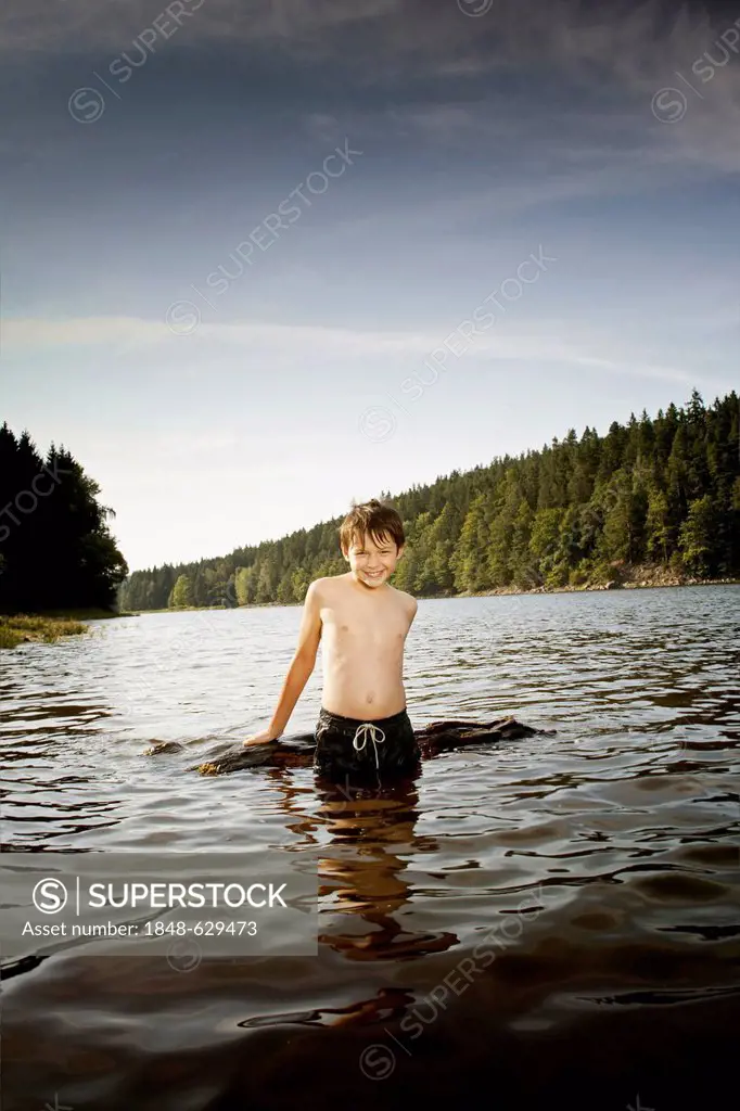 Boy playing with driftwood in a lake
