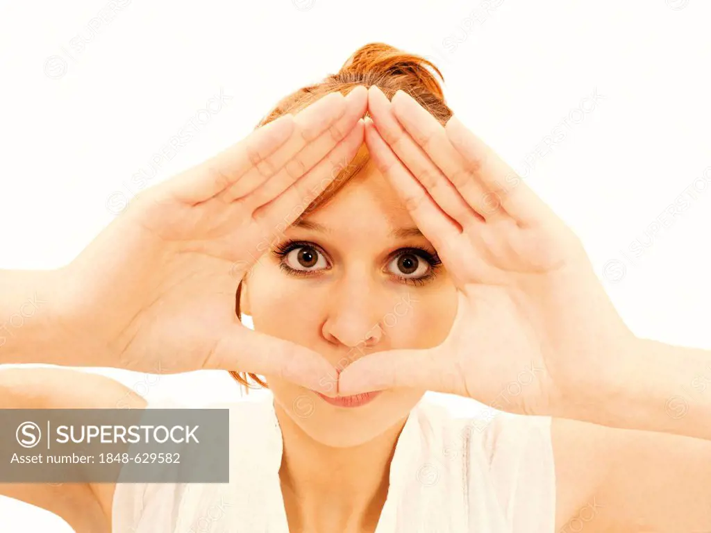 Young woman looking though her hands which form a triangle
