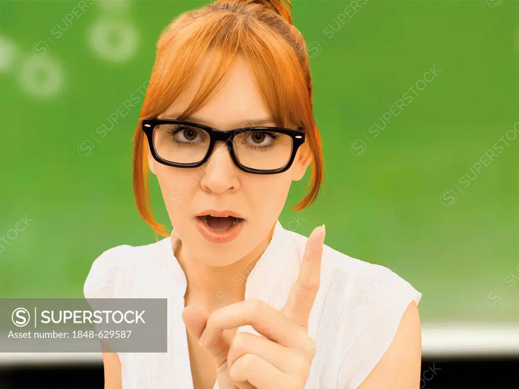 Young teacher with glasses wagging her finger admonishing someone in front of a school board