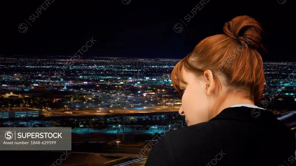Young businesswoman looking at the skyline at night