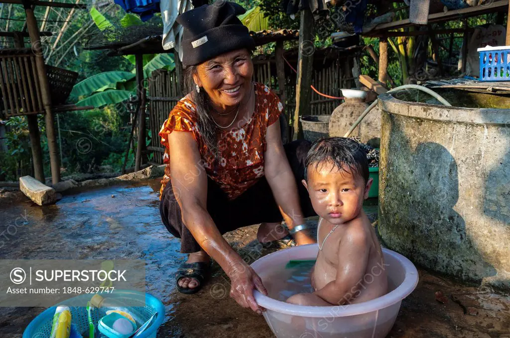 Woman bathing her child in a bowl, ethnic minority, village of hill tribe people, Hmong people, northern Thailand, Thailand, Asia