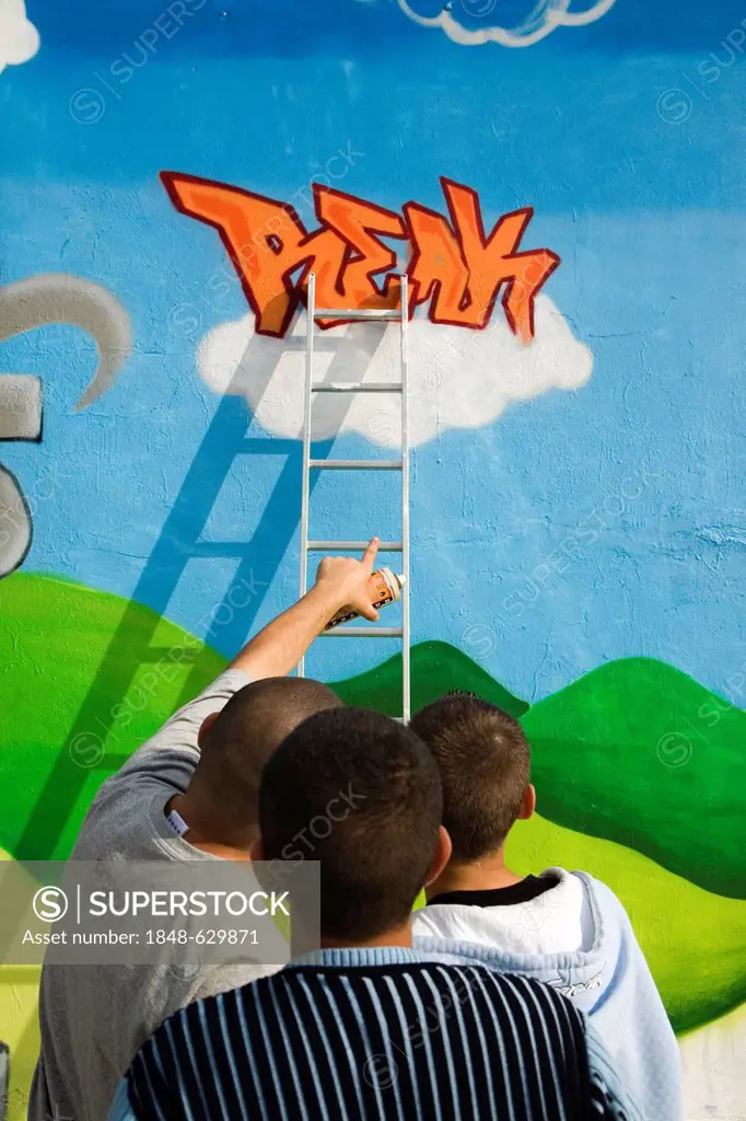 Young people of Turkish origin spraying legal graffiti on the wall of the Kreuzer youth centre at Goerlitzer Park, Kreuzberg district, Berlin, Germany...
