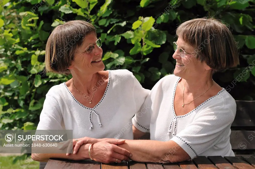 Two spry twin sisters sitting at a table in the garden