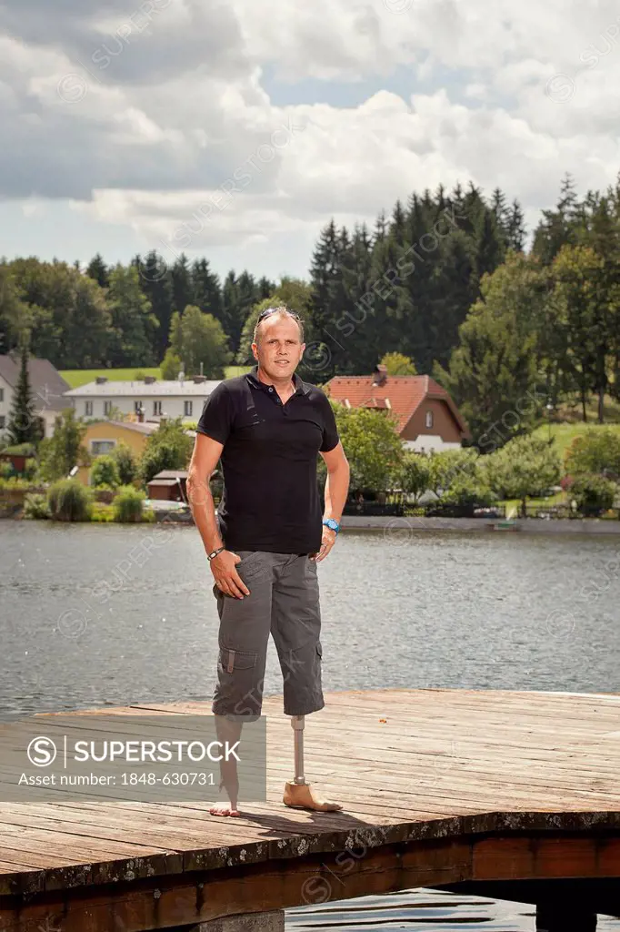 Man with a prosthetic leg sitting on a jetty