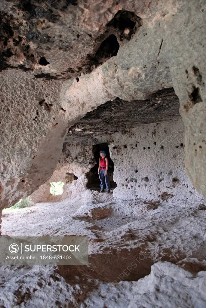 Tourist in one of the chambered tombs in the UNESCO world heritage site of the Sicel necropolis of Pantalica, situated in the Monti Iblei between Ferl...