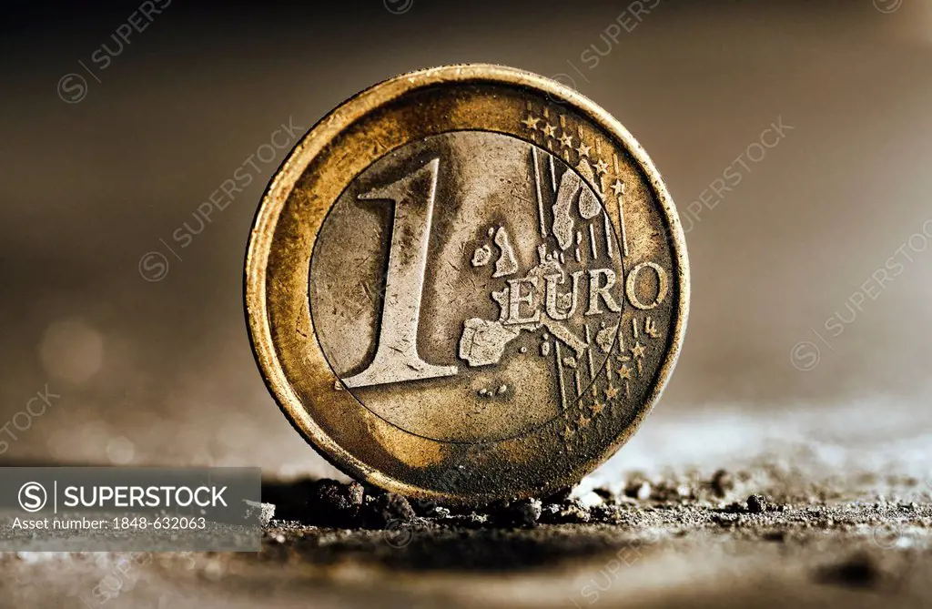 Burnt 1 euro coin in ashes, symbolic image for the euro crisis