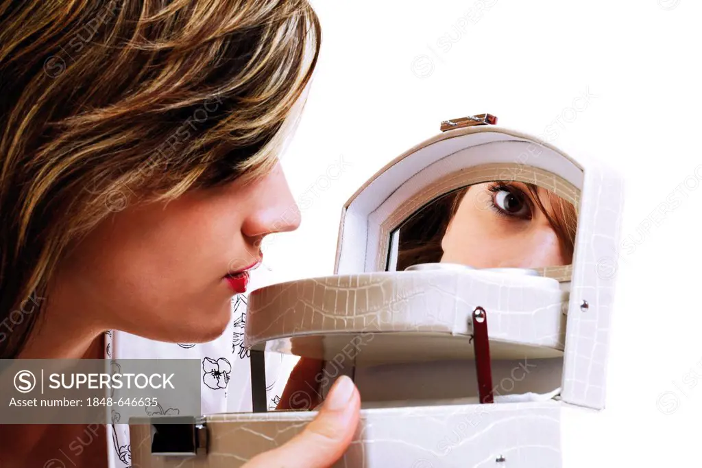 Young woman looking in the mirror of a cosmetic case