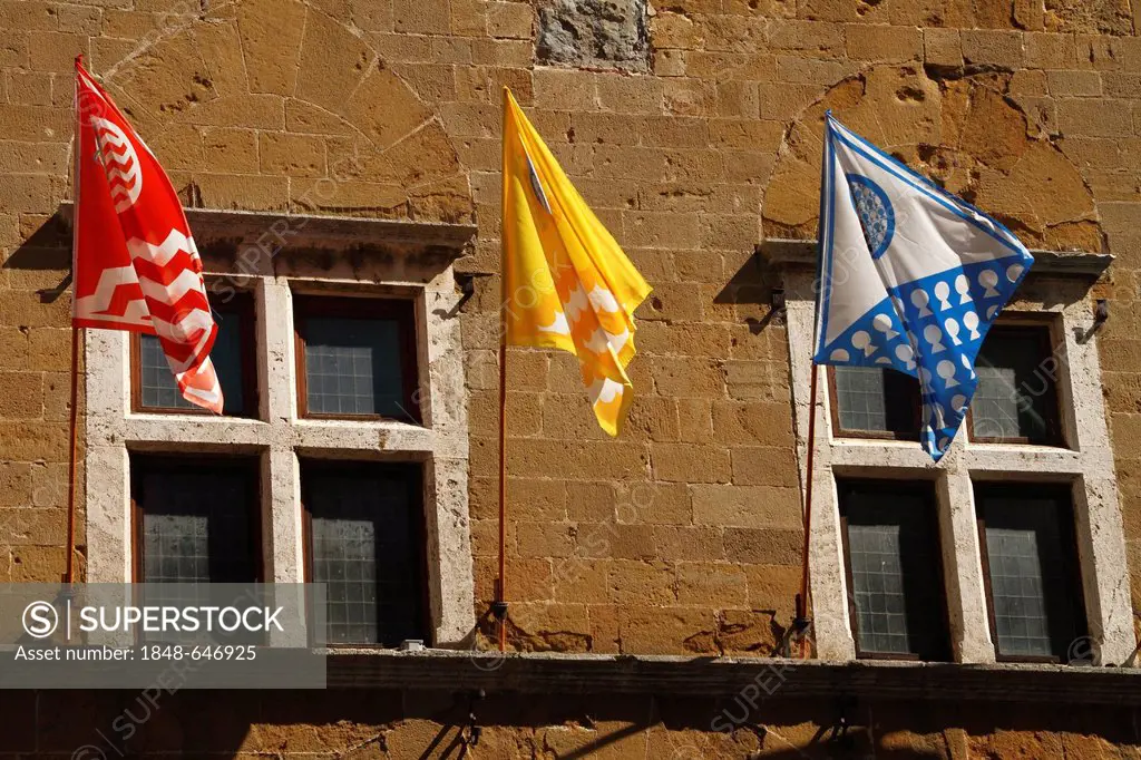 Colourful flags of the town in front of two windows of the Palazzo Vescovile in Pienza, UNESCO World Heritage Site, Orcia Valley, Tuscany, Italy, Euro...