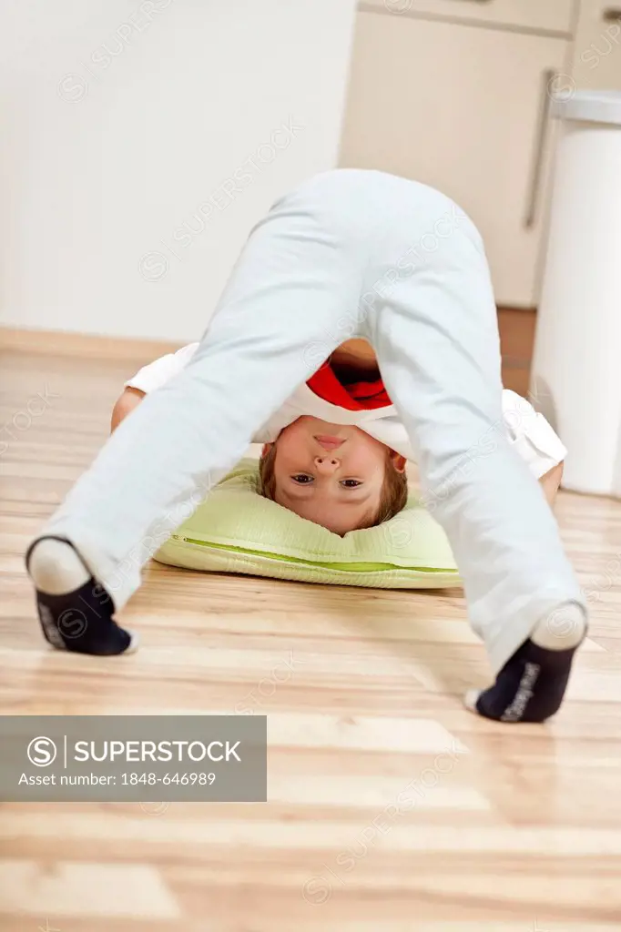 Boy doing gymnastics on the kitchen floor