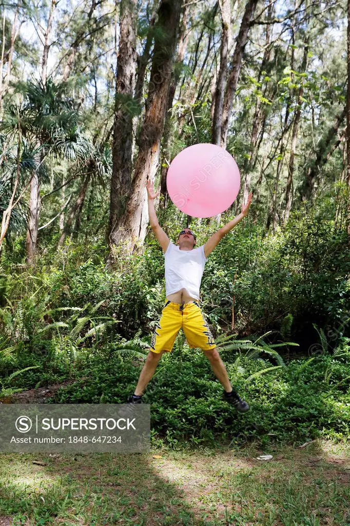 Man with a balloon in the woods, lightness and freedom, Nanawale Hills, Big Island, Hawaii, USA