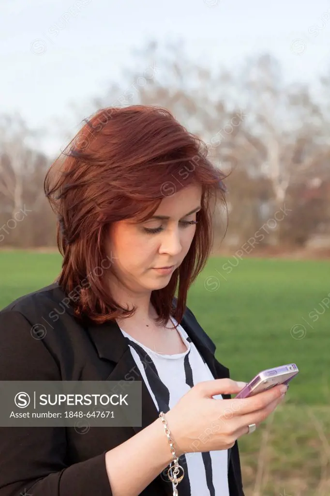Young woman, 25, writing a text message on an iPhone, Germany, Europe