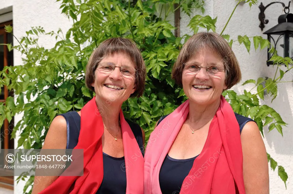 Two sprightly twin sisters, dressed alike and wearing red scarves, portrait