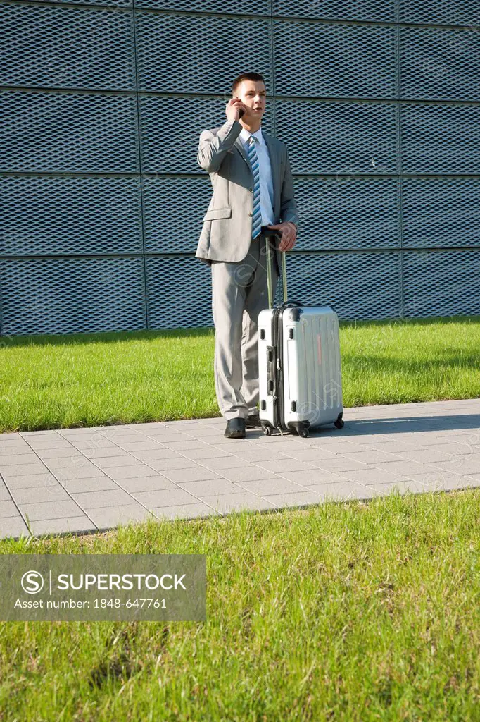 Businessman with a mobile phone and a trolley suitcase