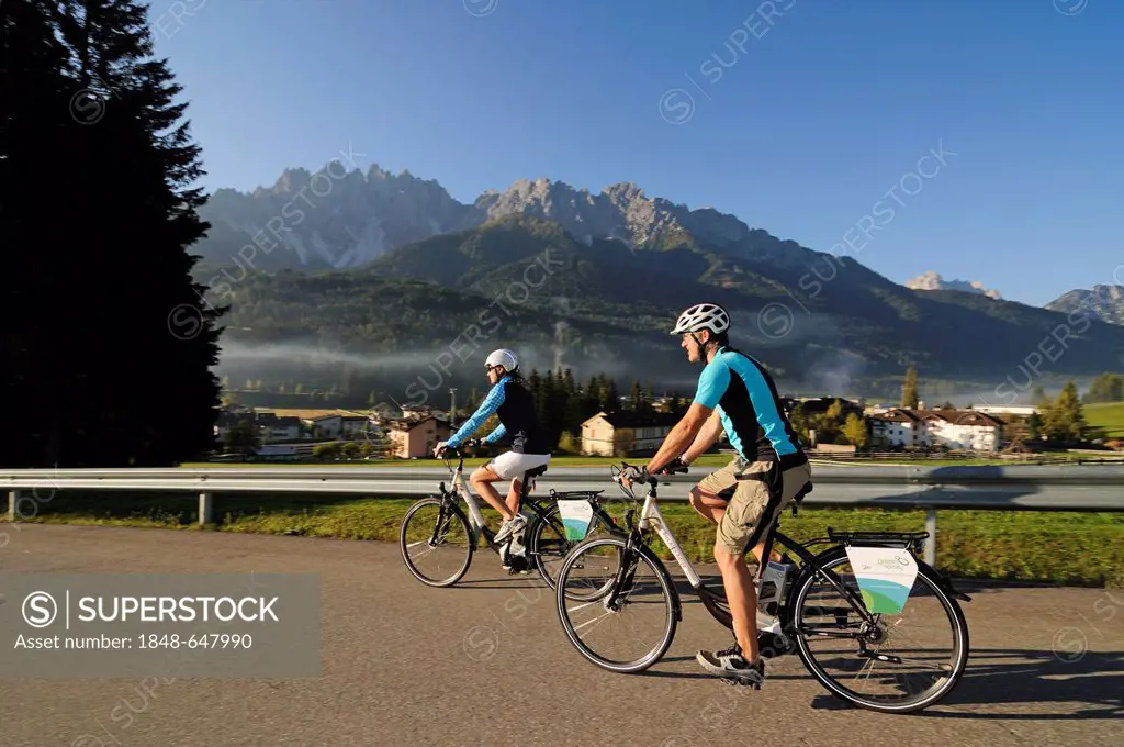 Couple riding electric bicycles, Innichen, Hochpustertal valley, Province of Bolzano-Bozen, Italy, Europe