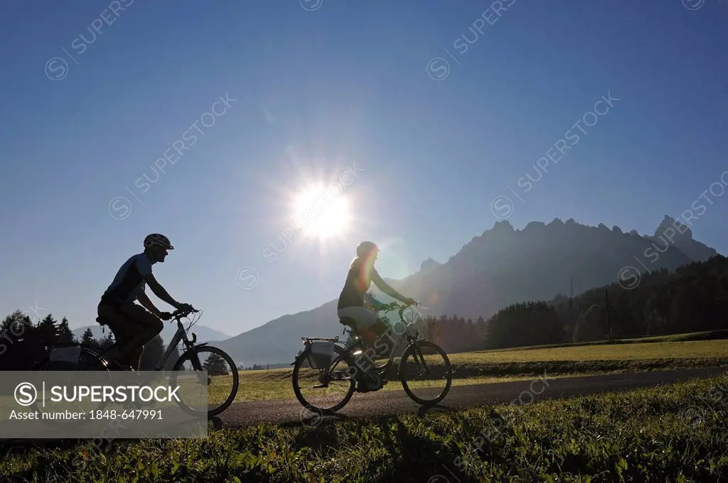 Couple riding electric bicycles, Innichen, Hochpustertal valley, Province of Bolzano-Bozen, Italy, Europe