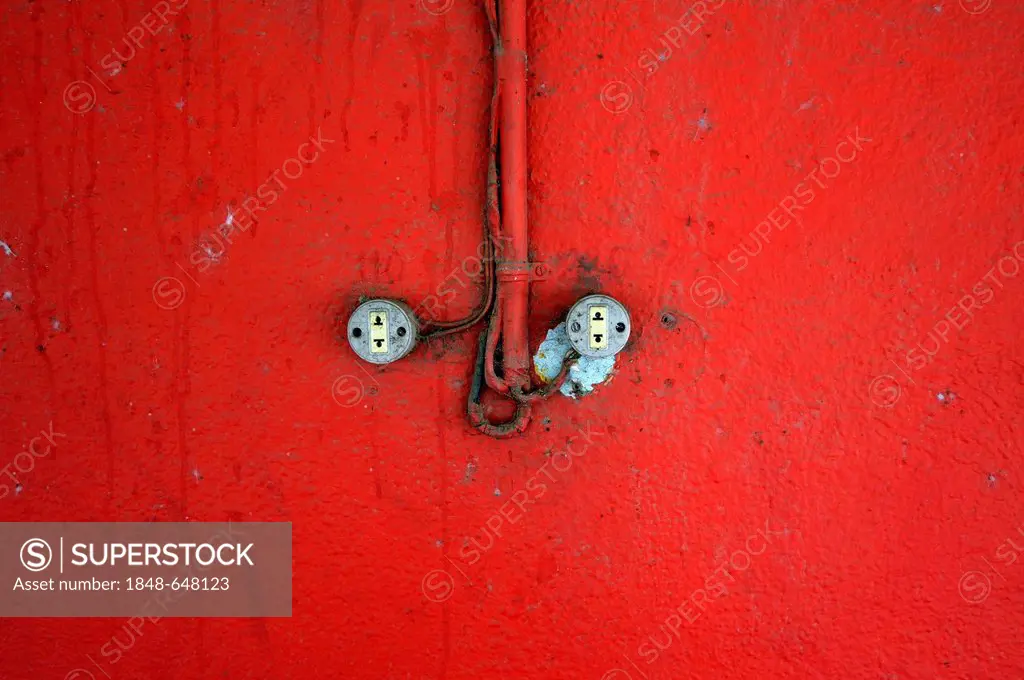 Shoddy electrical installation on a red wall