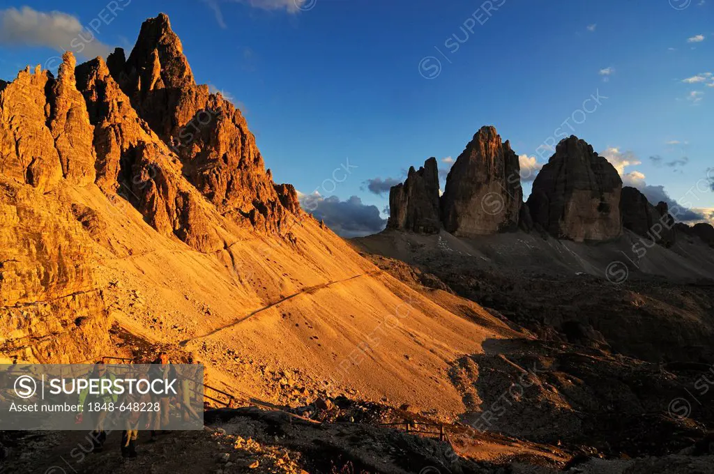 Hiking family on their way to Dreizinnen-Huette mountain lodge, Tre Cime di Lavaredo peaks at the back, Hochpustertal valley, Dolomites, Province of B...
