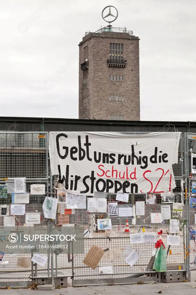 Protest posters against Stuttgart 21 railway project on a site fence, tower of the old railway station at back, Schlossgarten, castle gardens, Stuttga...