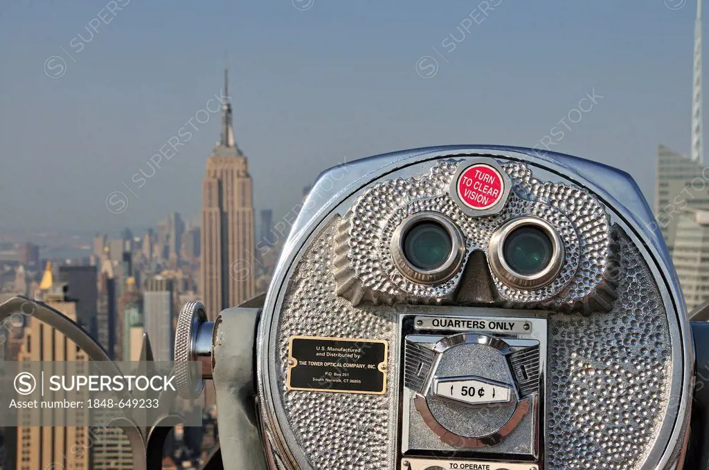 Coin-operated telescope on the observation deck Top of the Rock at the Rockefeller Center overlooking the Empire State Building and Downtown Manhattan...