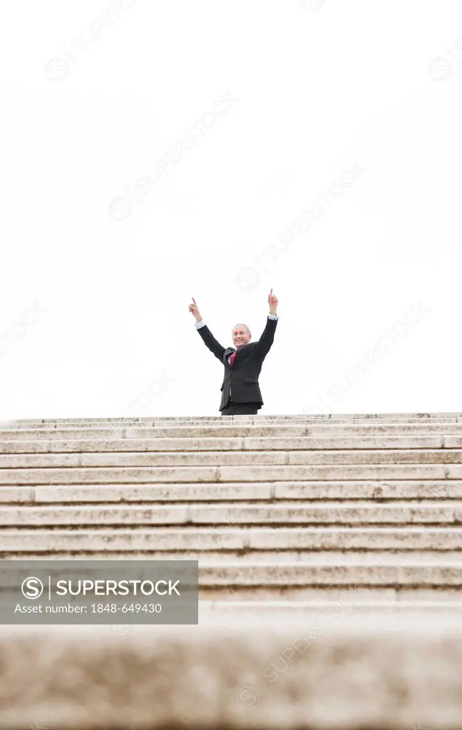 Businessman standing at the top of a staircase, cheering