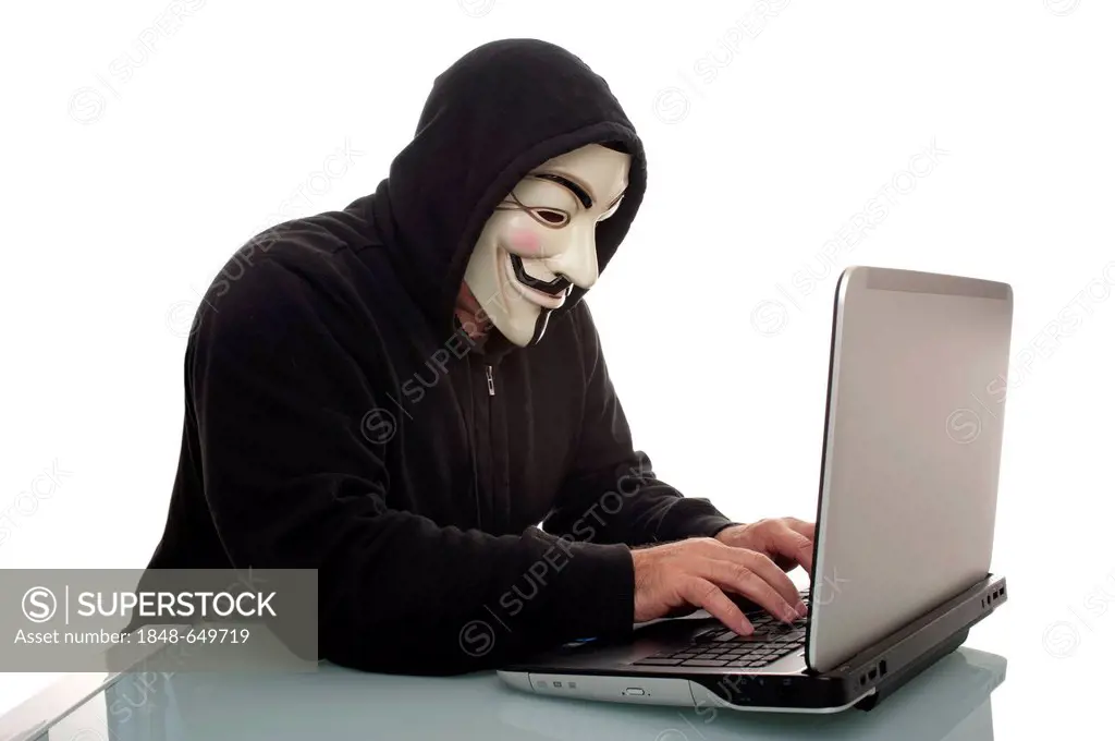Man wearing a Anonymous, Guy Fawkes or V for Vendetta mask, working on a laptop computer