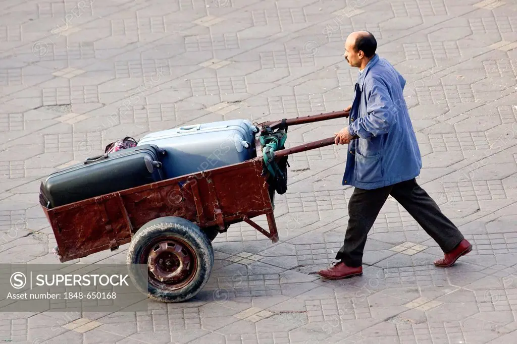 Man transporting suitcases with a handcart in Djemaa el Fna square, medina or old town, UNESCO World Heritage Site, Marrakech, Morocco, Africa