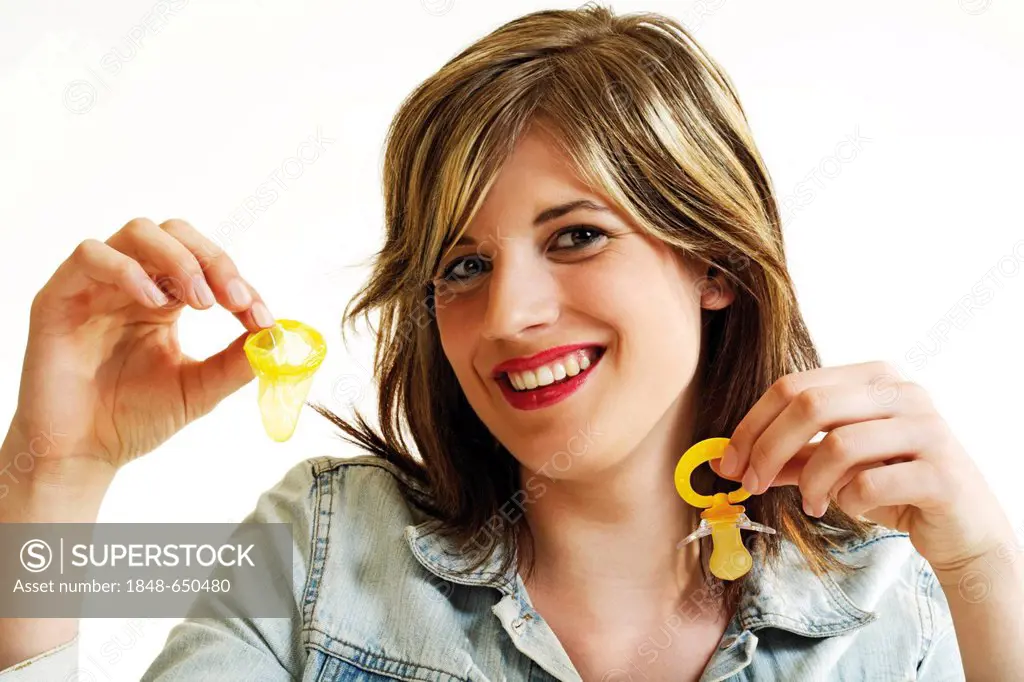 Young woman holding a condom in one hand and a dummy in the other