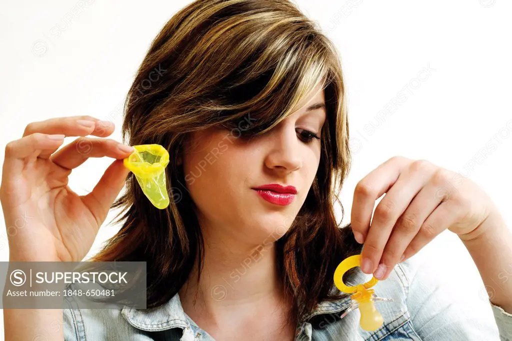 Young woman holding a condom in one hand and a dummy in the other