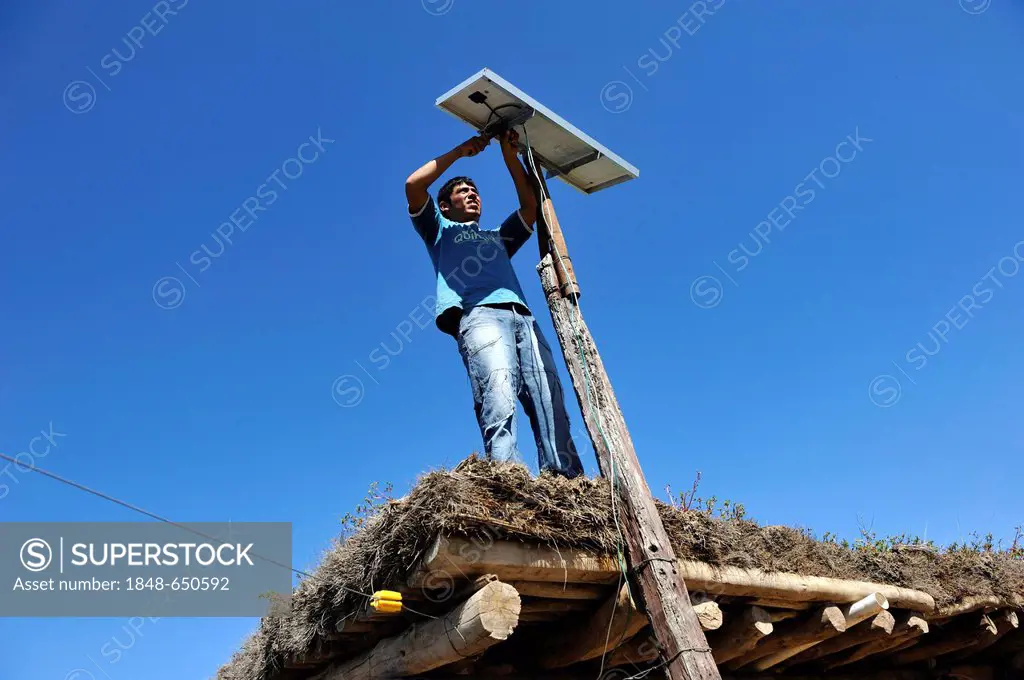 Young man mountain solar cells on the roof of a simple hut of a smallholder's farm, Gran Chaco, Santiago del Estero Province, Argentina, South America