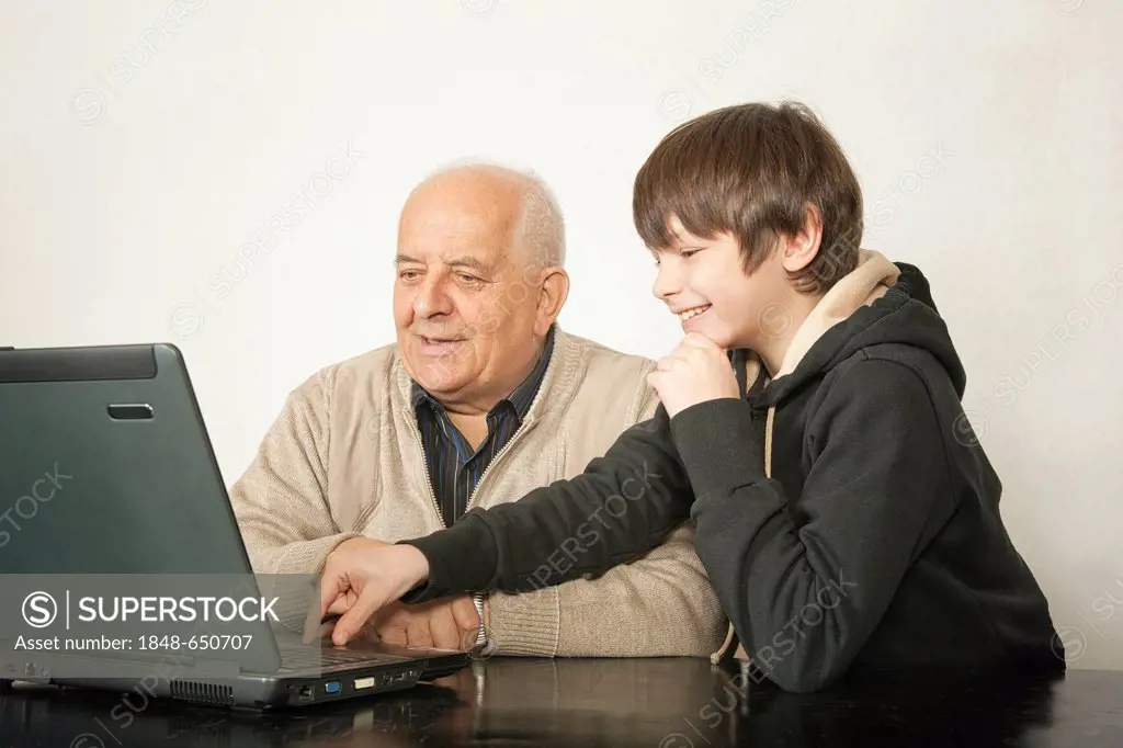 An Old man and a boy sitting in front of a laptop