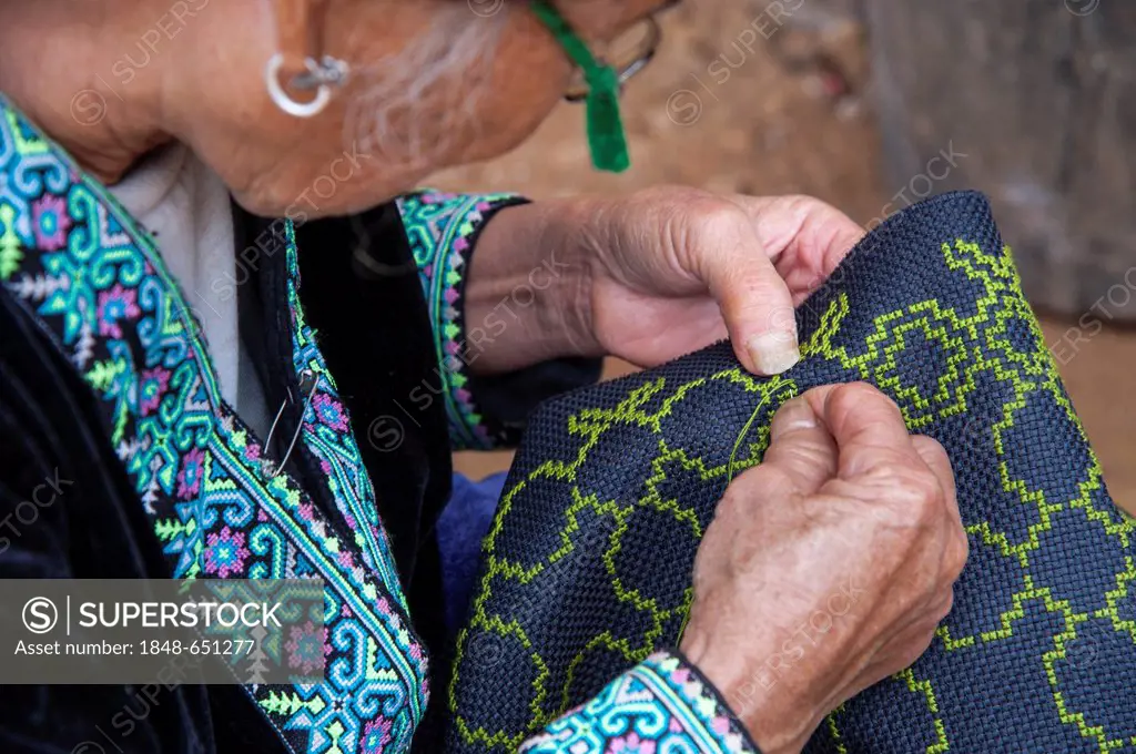 Elderly, traditionally dressed woman from the Black Hmong hill tribe, ethnic minority from East Asia, doing needlework, embroidery, Northern Thailand,...