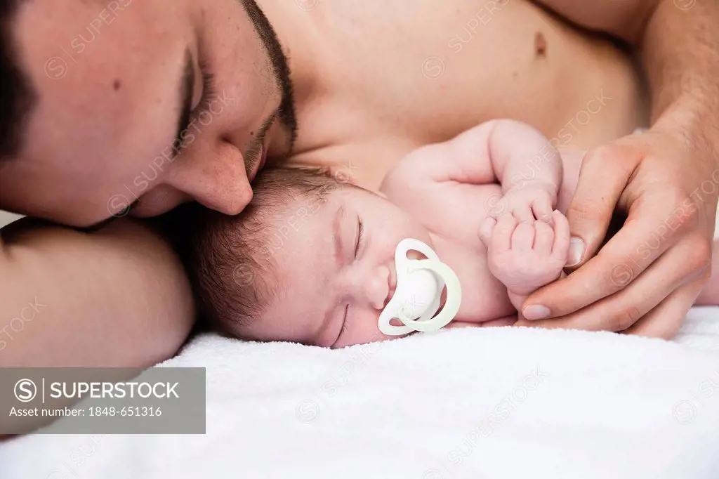 Father lovingly cuddling his newborn baby