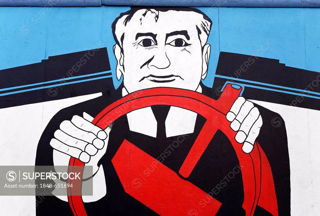 Gorbachev sitting behind a steering wheel made from the Communist hammer symbol, painting on the remants of the Berlin Wall, Friedrichshain district, ...