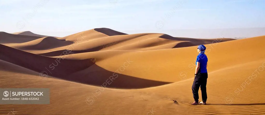 Woman walking in the dunes, Erg Chegaga region, Sahara desert near Mhamid, Morocco, Africa