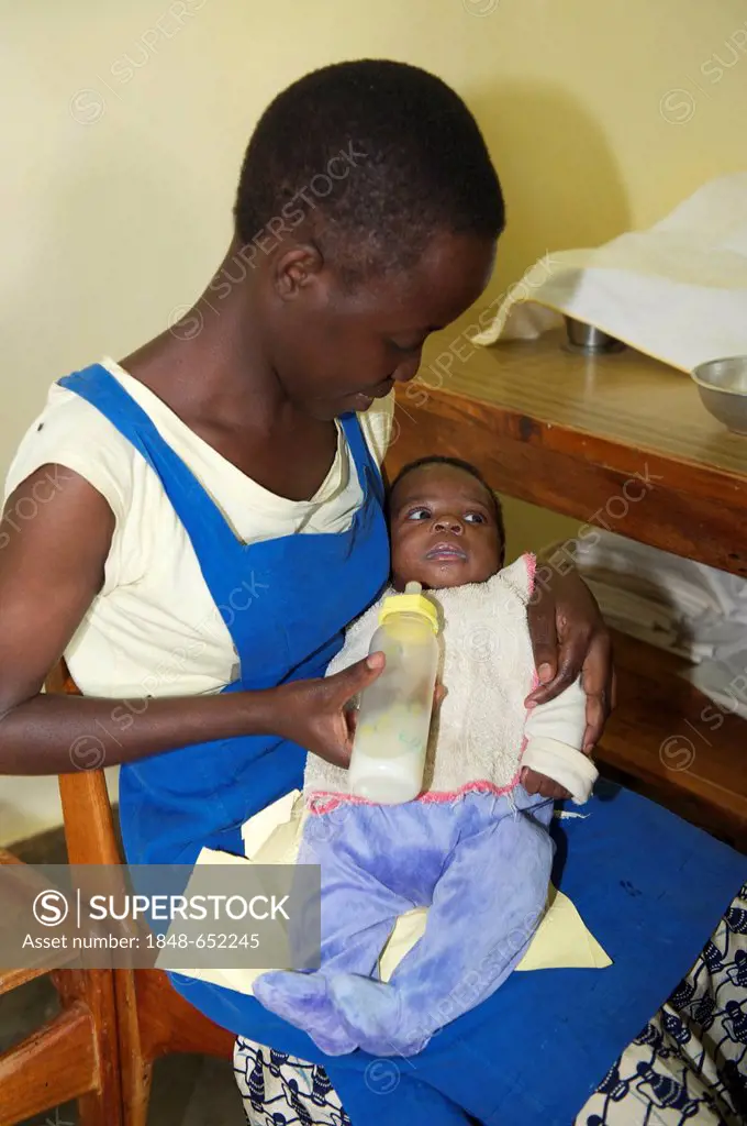 Infant being fed with a bottle by a children's nurse in an orphanage near Bukoba, Tanzania, Africa
