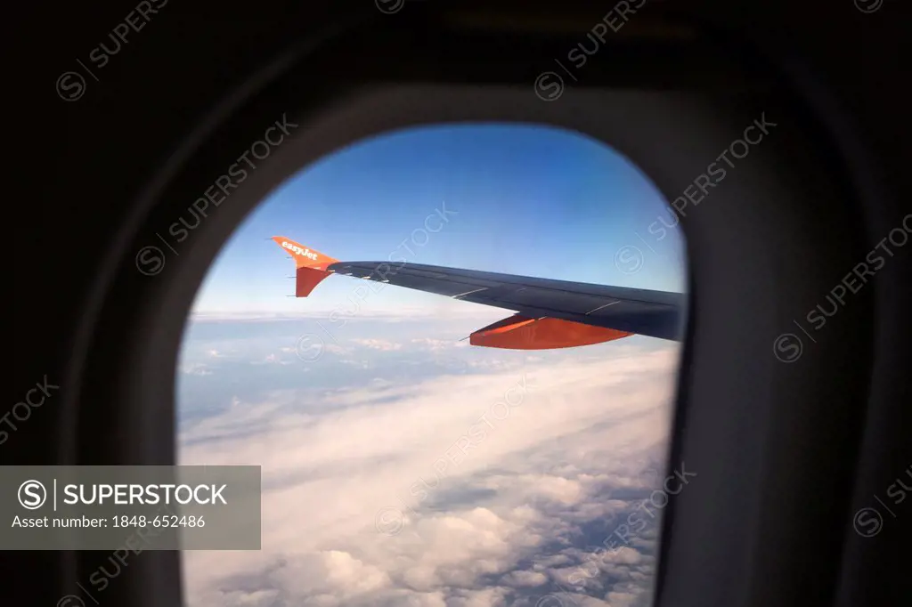 View through the cabin window to the left wing of an Airbus A319-100 of the easyJet airline, in flight