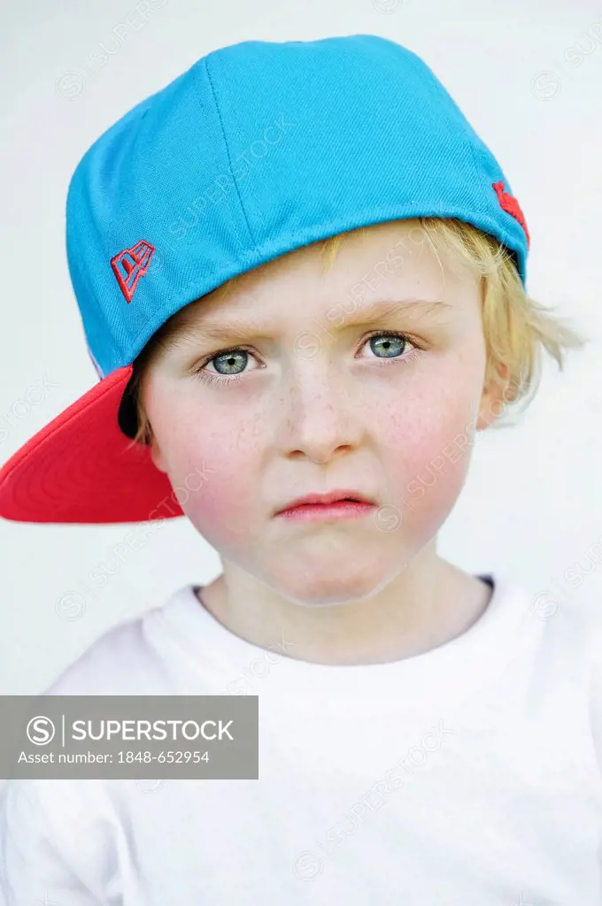 Little boy wearing a baseball cap with a sad face