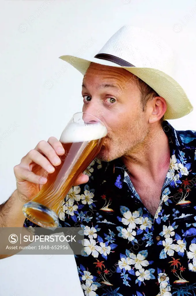 Man wearing a straw hat and a Hawaiian shirt drinking wheat beer