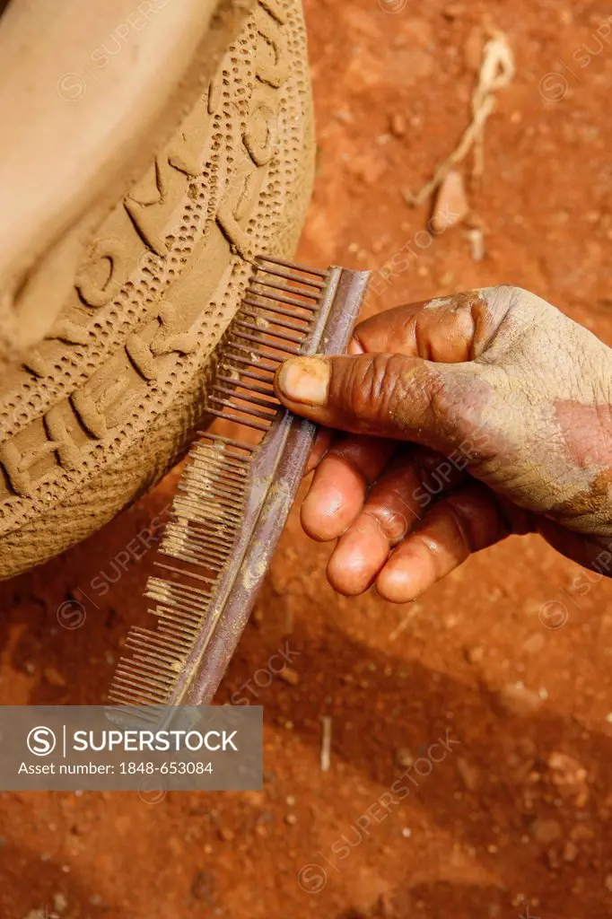 Woman using a comb to apply a pattern to traditional pottery, Babessi, Cameroon, Africa