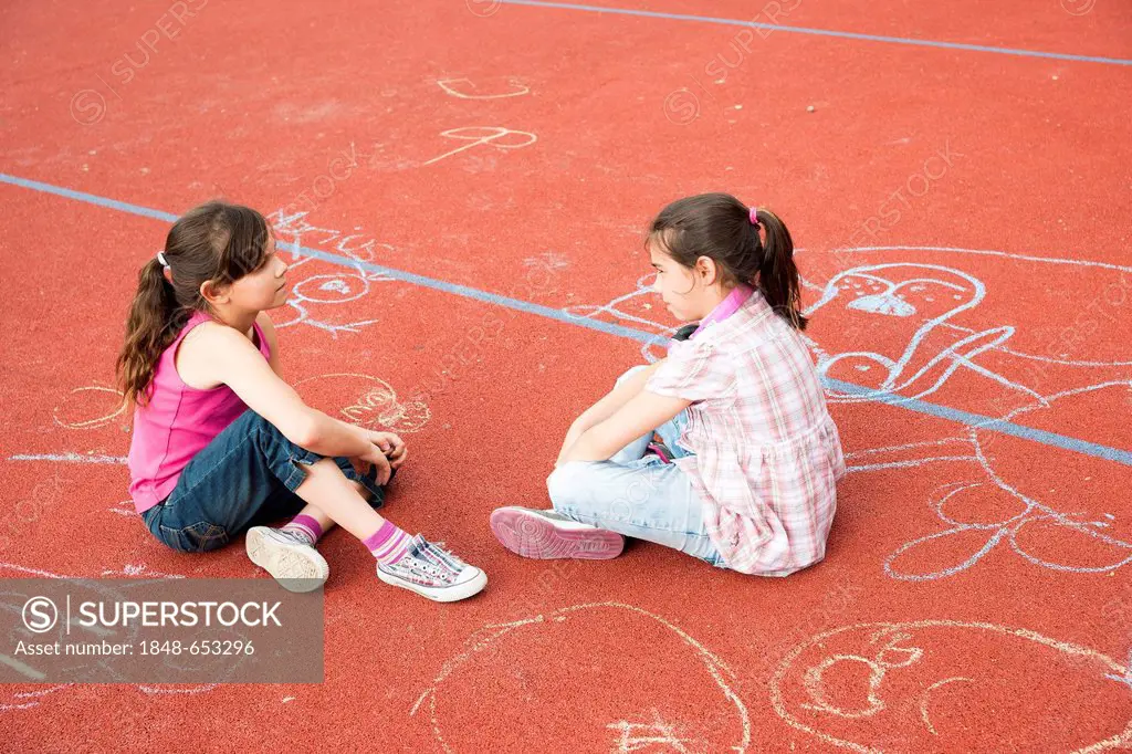 Two girls sitting around bored on the school playground