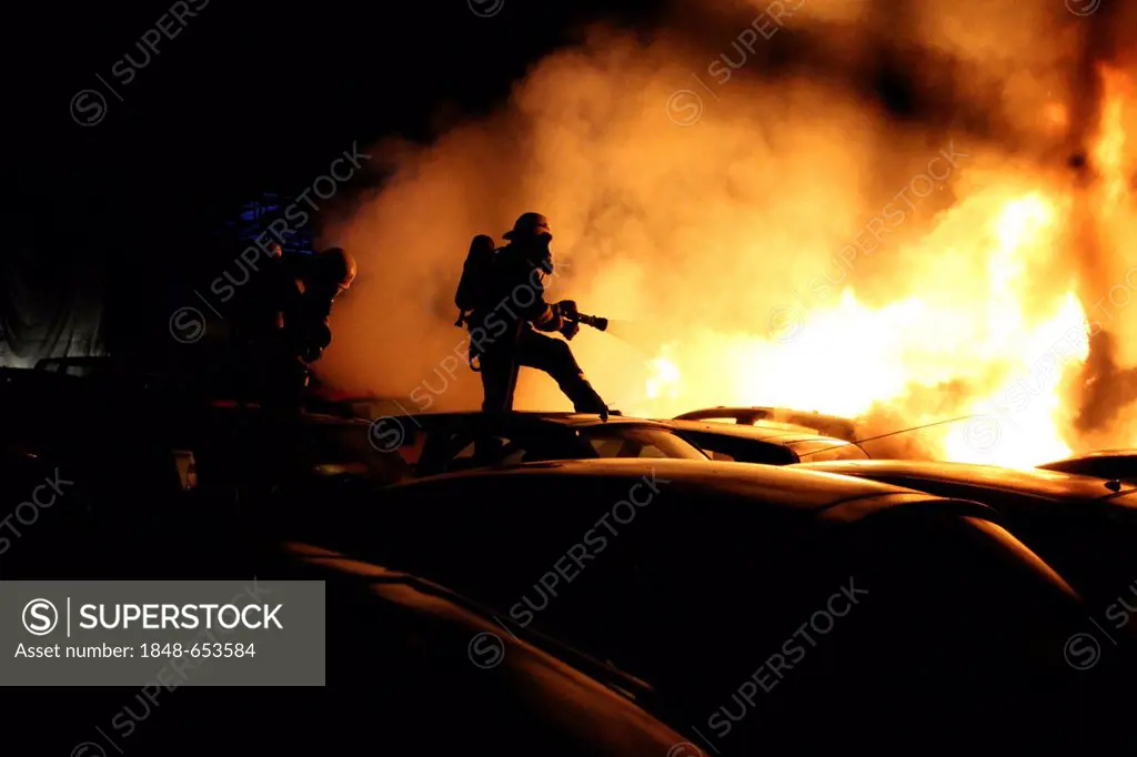 Arson attach on cars, firefighters trying to extinguish burning cars in the car park of a car dealer in Berlin-Schmoeckwitz, Berlin, Germany, Europe