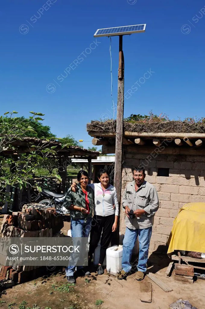 Farming family standing in front of their hut with a solar cell, Gran Chaco, Santiago del Estero Province, Argentina, South America